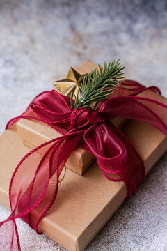 Close-up of two Gift boxes decorated with a fir sprig and star ornament and red ribbon tied in a bow