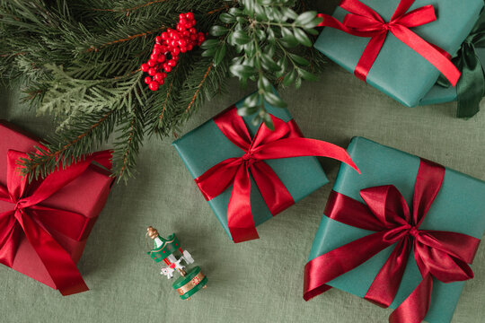 Overhead view of assorted wrapped Christmas gifts on a table with a handmade Christmas wreath and a carousel ornament