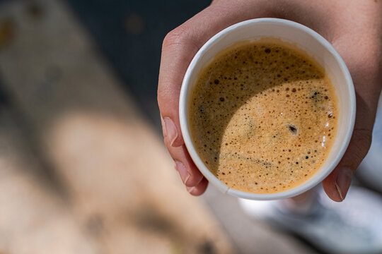 Close-up overhead view of teenage boy holding a cup of coffee in a disposable paper cup