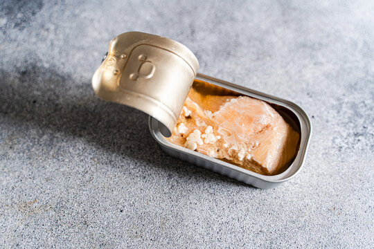 Close-up of an open tin of canned salmon on a concrete worktop