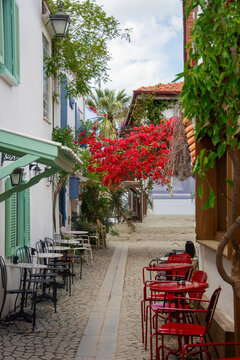 Narrow cobblestone street with cafe chairs and tables, Alacati, Cesme Peninsula, Izmir Province, Turkey,