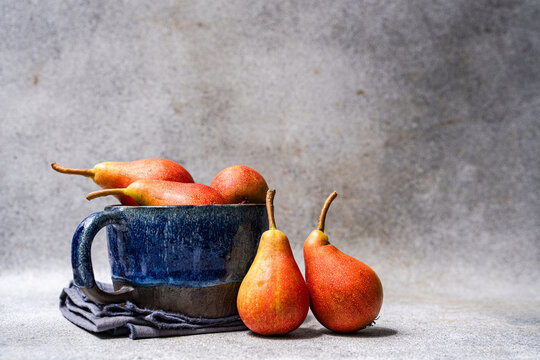 Side view of a cup of ripe pears on a grey ceramic worktop