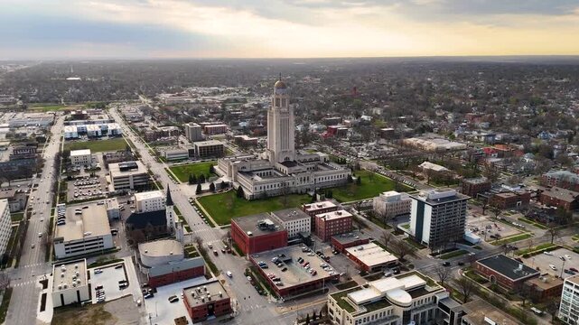 Majestic drone footage of the Nebraska State Capitol in Lincoln, Nebraska, USA, featuring the iconic government tower topped with The Sower statue, surrounded by downtown streets 