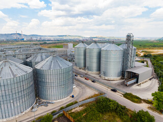 Large grain storage facility located outside a city with silos and trucks visible on a clear day © DSMT