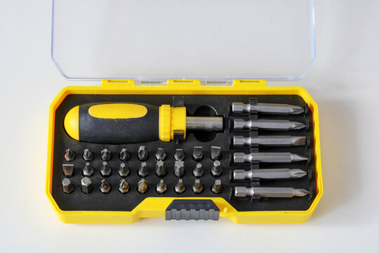 Screwdriver bit set in an open yellow plastic case lies on a white background. Hand tool kit, home repair, and hardware equipment concept for DIY construction projects.