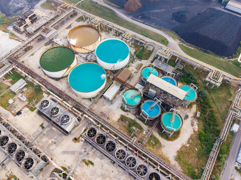 Water treatment facility with large tanks and industrial structures in the background during daylight