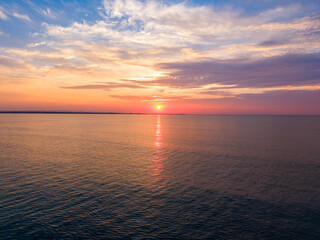 Obraz premium Sunset over water with horizon and clouds in evening light