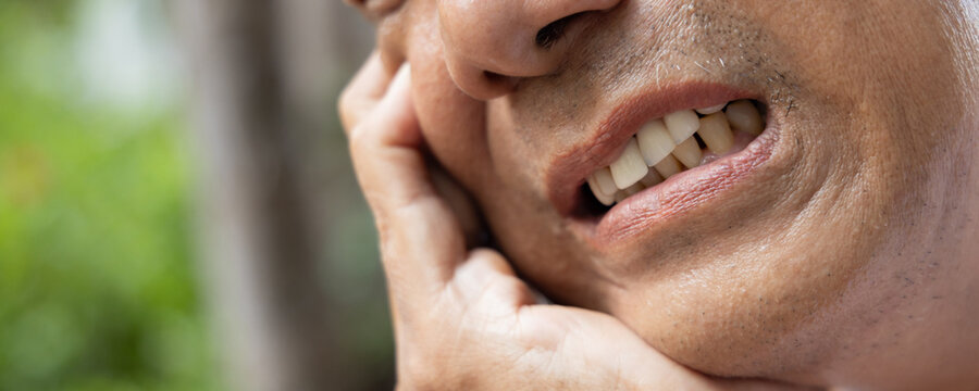 Old asian senior man with crooked teeth suffering from toothache, tooth decay, tooth sensitivity, teeth grinding problem, concept image for oral health care or dental care, mouth closeup shot