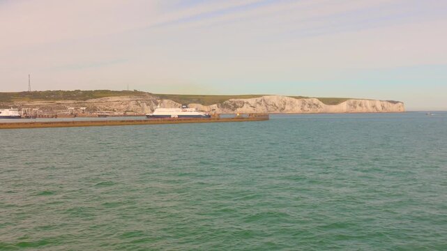 Scenic view of the famous white cliffs of Dover from the English Channel, with a ferry boat nearby. Iconic British coastline, maritime travel, and beautiful sea landscape.