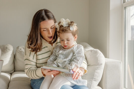 Mother reads a storybook with her toddler daughter at home