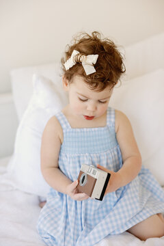 Curious toddler girl explores a vintage camera at home
