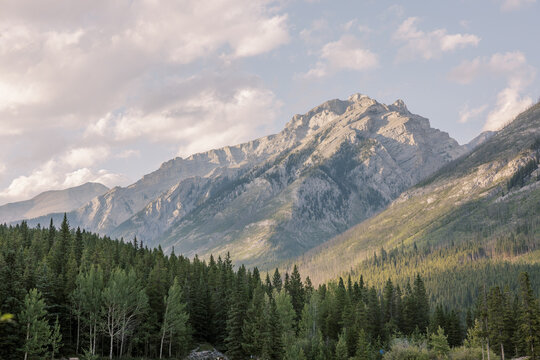 Sunlight on rugged mountain above evergreen forest in Banff, Alberta