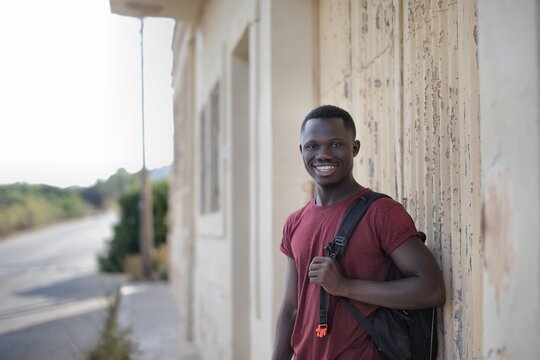 Young Black man with a backpack smiling outdoors