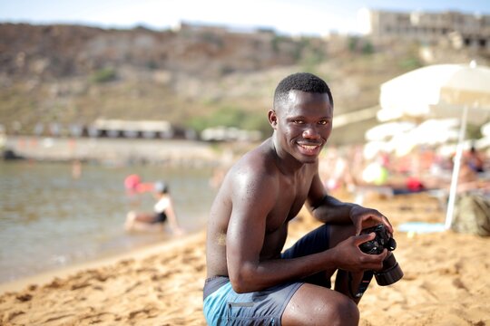 Happy man with a camera enjoying a sunny beach day
