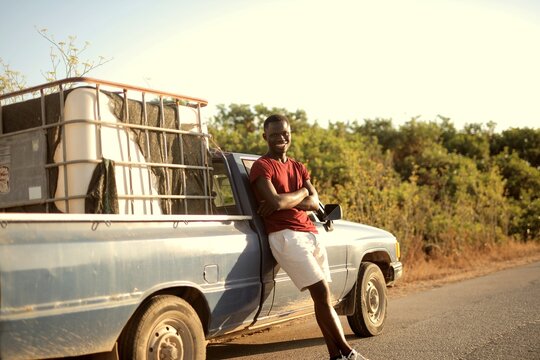 Young man smiling leaning against his pickup truck