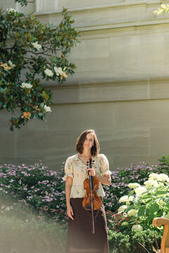 Woman violinist holding her instrument in a sunny garden