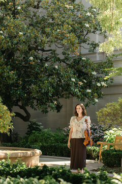 Violinist stands thoughtfully in a blooming garden
