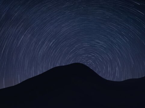 Mesmerizing night sky with star trails over mountain silhouette