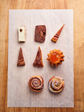 Assorted pastries and desserts arranged on parchment paper, perfect for bakery menus or cafe promotions