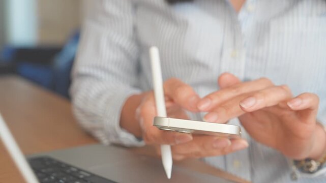 Smartphone Touchscreen Interaction, Remote Worker Taps Mobile Phone Beside Laptop While Holding Stylus, Close Up Showing Online Communication, Digital Productivity And Cross Device Workflow At Home