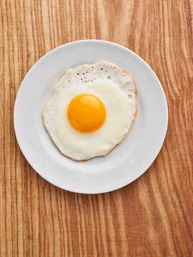 Fried egg on a white plate, perfect for breakfast or brunch menu, simple and nutritious option for food delivery