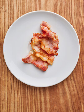 Crispy bacon strips served on a white plate, breakfast menu, indulgent morning meal concept