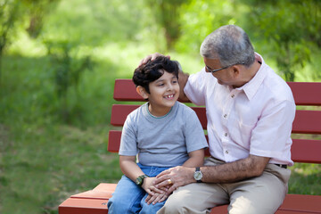 Fototapeta premium Grandfather and grandson sitting in a park