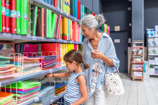 Grandmother and granddaughter choosing school supplies in store