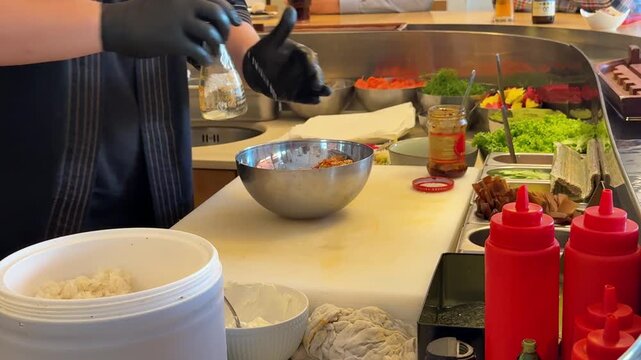 Chef drizzling sauce on salad, Japanese restaurant food preparation close up