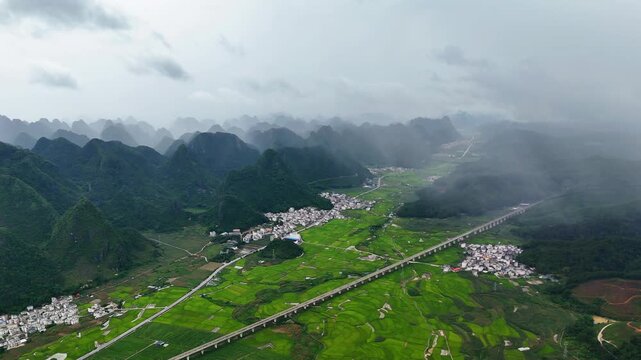Localized Summer Rain Over Karst Mountains and Green Rice Fields with Railway