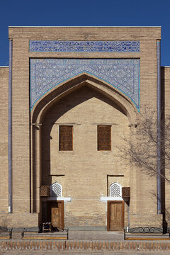 Iwan portal of Muhammad Amin Khan Madrasa in Ichan Kala featuring blue tilework and Arabic inscriptions. Historic brick facade in Khiva, Uzbekistan, ideal for travel and architecture publications.