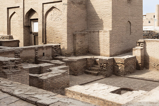 Ancient brick ruins and arched walls inside Ichan Kala in Khiva, Uzbekistan. Exposed foundations and weathered brickwork illustrate centuries of Central Asian architectural heritage.