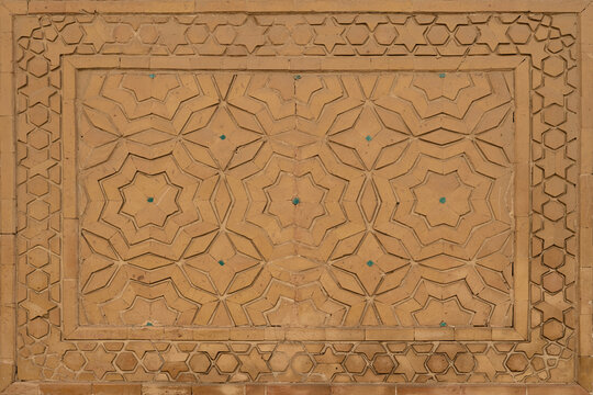 Geometric star pattern ganch carved in terracotta brickwork on a historic Islamic building in Bukhara. Intricate detail ideal for architecture, heritage, and design projects.