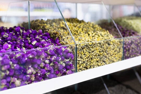 Dried flowers and herbal tea displayed in glass bins at an oriental bazaar in Bukhara. Colorful purple and yellow blossoms create a vivid market scene ideal for travel and wellness imagery.