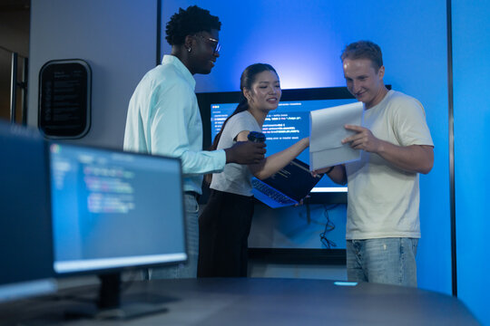 Diverse software developer team collaborating on computer code in modern IT office, Male programmers and female colleague brainstorming future technology business innovations and smart digital system