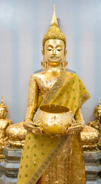 Golden Standing Buddha Statue Holding an Alms Bowl Inside a Thai Temple