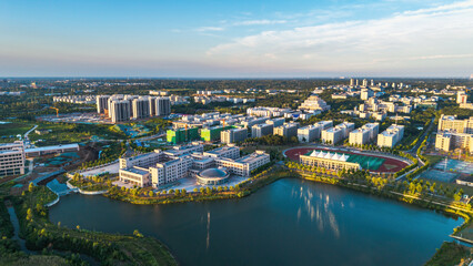 Obraz premium An aerial shot of a modern campus featuring lakeside buildings, sports facilities and green spaces under clear sky.
