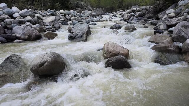 Rapid mountain river with powerful whitewater flowing over large rocky boulders in Svaneti Georgia