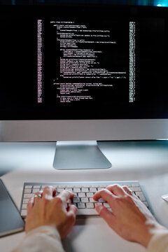 Hands of young female programmer typing on keyboard while decoding data