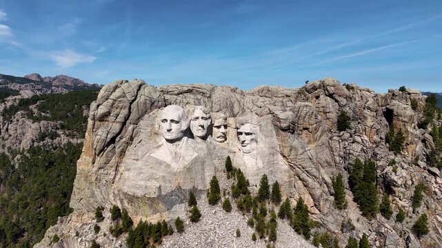 Cinematic drone footage of Mount Rushmore National Memorial in South Dakota, USA, showcasing the monumental granite sculptures of four American presidents surrounded by the scenic Black Hills