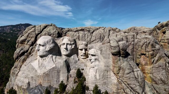 Cinematic drone footage of Mount Rushmore National Memorial in South Dakota, USA, showcasing the monumental granite sculptures of four American presidents surrounded by the scenic Black Hills