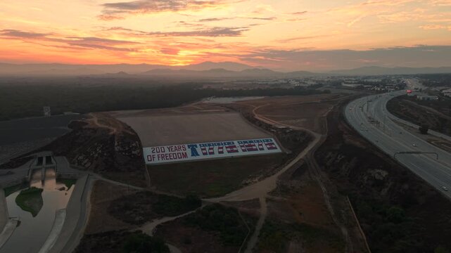 This aerial drone shot has an eerie feel to it. The foreground shows a bicentennial monument at Prado Dam while the background hides a bright orange glow as the sun struggles to burn away the clouds