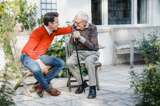 Happy man talking with father on chair