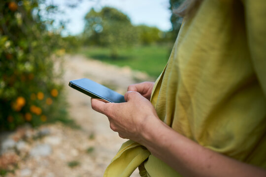 Woman text messaging through smart phone at garden