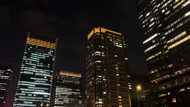 夜の丸の内・大手町オフィス街で見上げる丸ビル周辺の超高層ビル群と窓明かりの夜景。