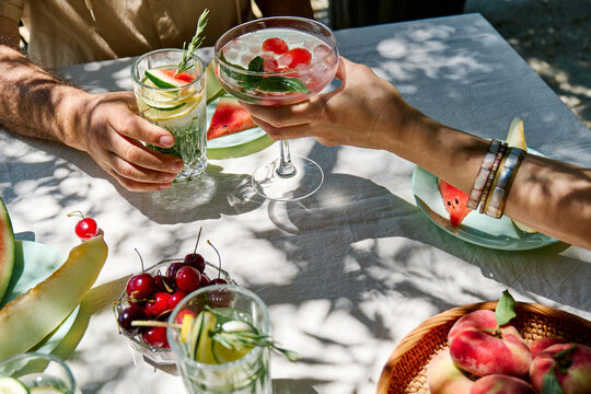 Man and woman toast with a refreshing cocktail at an outdoor table