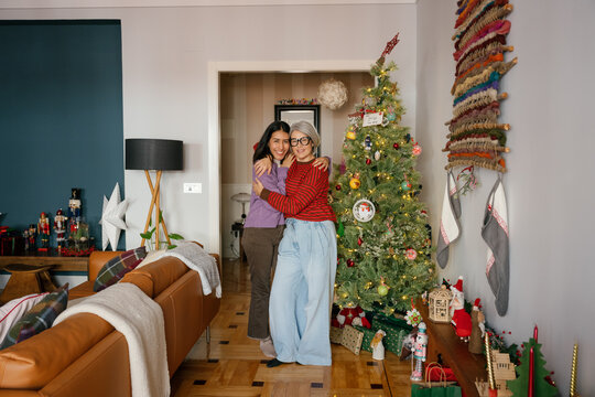 Mother and daughter hug near a Christmas tree at home