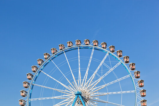 A large Ferris wheel stands against a blue sky at Munich Oktoberfest