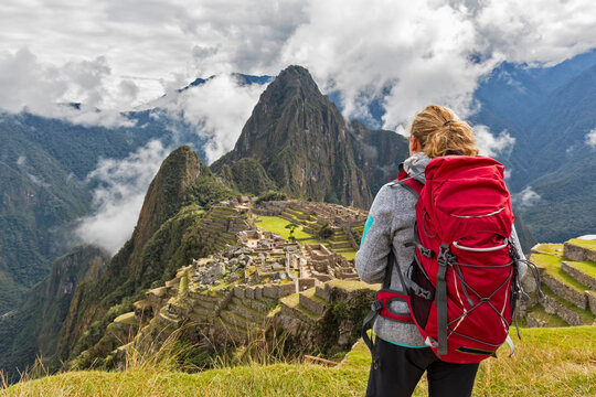 Peru, Andes, Urubamba Valley, tourist with red backpack at Machu Picchu with mountain Huayna Picchu