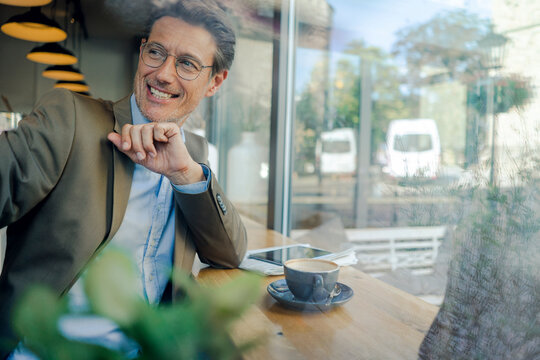 Mature businessman sitting in coffee shop, smiling